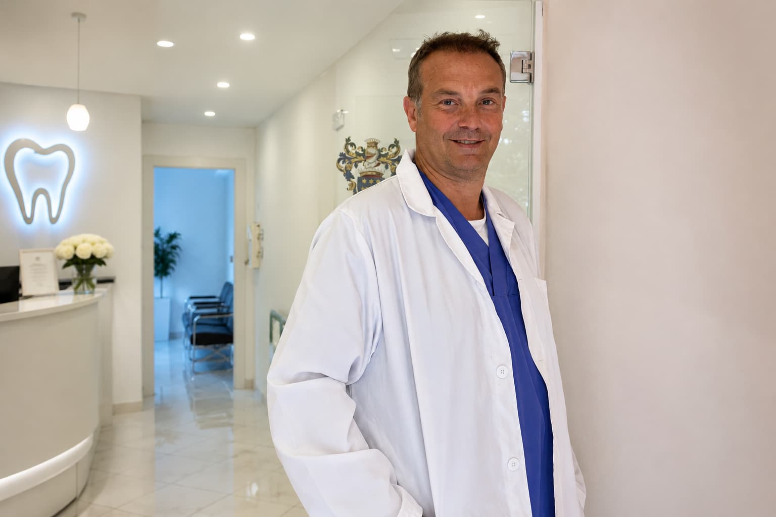 Il Dott. Fabrizio Avidano sorridente in camice bianco alla reception.
